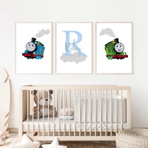 Peut inclure: Trois impressions encadrées représentant des trains de dessins animés. L'une montre un train bleu avec un visage souriant et de la fumée. Une autre présente la lettre bleue "R" avec le nom "Riley". La troisième affiche un train vert avec un visage souriant.