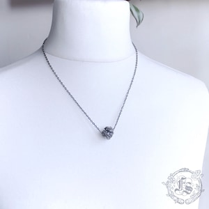 May include: A silver chain necklace with a textured silver ball pendant.