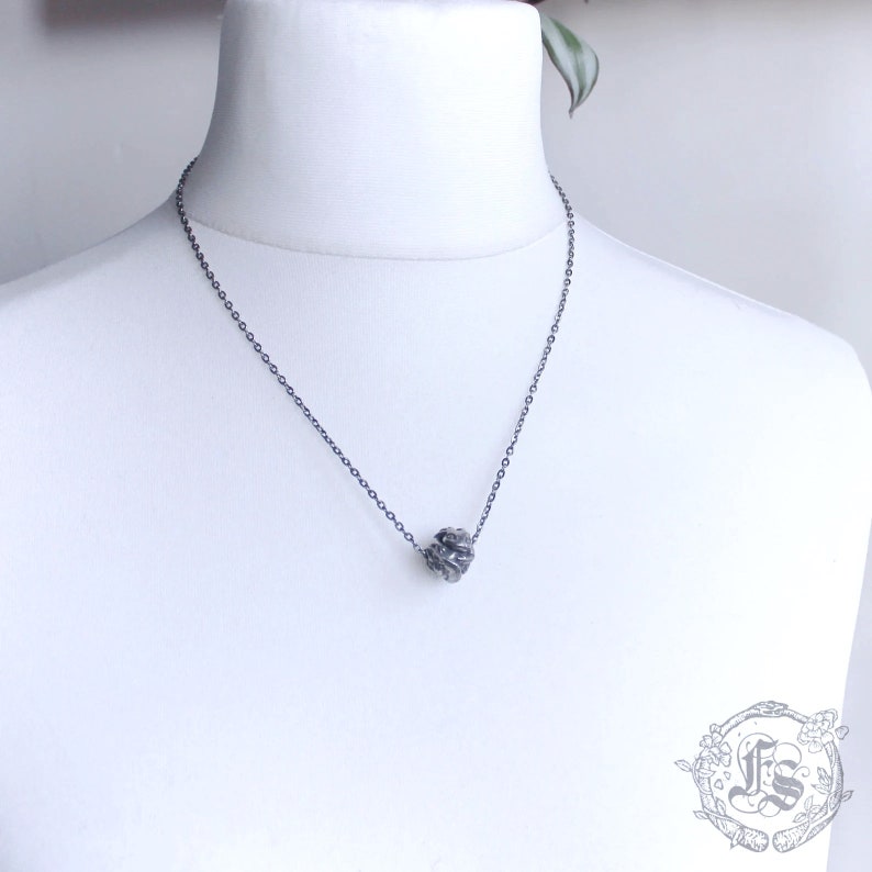 May include: A silver chain necklace with a textured silver ball pendant.