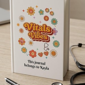 May include: A white hardcover journal featuring the text Vitals Vibes in a retro font, surrounded by colorful smiley face flowers, a small stethoscope icon, and the printed text This journal belongs to Kayla at the bottom of the cover.