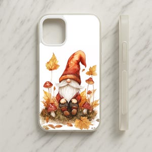 May include: A clear phone case featuring a watercolor illustration of a gnome with a long white beard and a tall red hat, surrounded by orange autumn leaves and small red mushrooms with white spots on a white background.