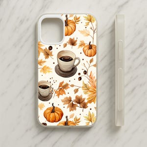 May include: A clear phone case featuring a repeating pattern of orange pumpkins, beige coffee cups on dark saucers, and scattered autumn leaves in shades of yellow, orange, and brown against a cream-coloured background with small dark brown dots.