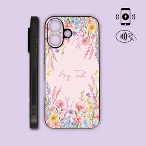 May include: A black smartphone case featuring a light pink background decorated with a watercolour floral pattern of pink, yellow, and blue wildflowers. The centre displays the text Any Text. Icons for wireless charging and NFC are visible.