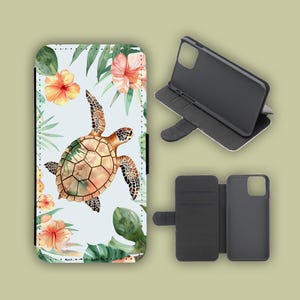 Könnte beinhalten: Eine Handyhülle mit einem Aquarelldesign mit einer Meeresschildkröte, Hibiskusblüten und tropischen Blättern. Die Hülle ist geöffnet und zeigt das Innere des Telefons. Sie verfügt über einen Magnetverschluss und schützt das Telefon.
