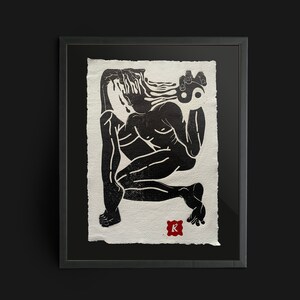 Op de afbeelding: Een zwart-witte linosnede op getextureerd papier met een gehurkte figuur met vloeiend haar die een yin-yang symbool vasthoudt. Het kunstwerk zit in een zwarte lijst en bevat een kleine rode vierkante stempel met de letter R in de hoek.