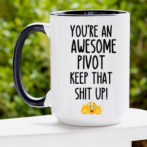 Könnte beinhalten: Weißer Keramikbecher mit schwarzem Henkel und Rand. Der Becher zeigt den Text "YOU'RE AN AWESOME PIVOT KEEP THAT SHIT UP!" in Schwarz, zusammen mit einem Daumen hoch Emoji.