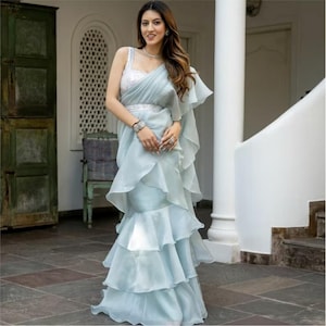 Los saris con volantes azules para el cóctel de recepción de bodas son prendas indo-occidentales de diseñador para mujeres que están listas para usar.