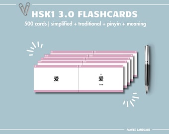 Op de afbeelding: HSK1 3.0 flashcards met 500 kaarten, inclusief vereenvoudigde en traditionele karakters, pinyin en betekenis. De kaarten hebben een witte achtergrond met roze randen. Een zilveren pen en paperclips zijn ook in de afbeelding.
