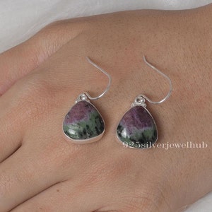 Peut inclure: Une paire de boucles d'oreilles en argent avec des gouttes de pierres précieuses vertes et roses. Les boucles d'oreilles ont un design simple à crochet.