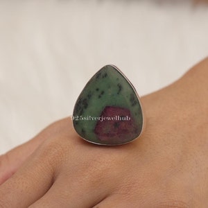 Puede incluir: Un anillo de plata con una piedra preciosa verde y rosa en forma de lágrima. El anillo está engastado en plata de ley y presenta una piedra natural única.