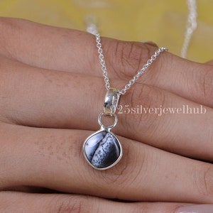 May include: A silver chain necklace with a pendant featuring a black and white dendritic opal stone. The pendant is set in sterling silver and has a simple design.