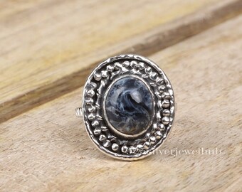 Puede incluir: Un anillo de plata con una piedra ovalada gris y blanca engastada en un engaste texturizado y con cuentas.