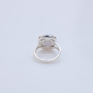 May include: A silver ring featuring a square-shaped, light purple gemstone set in a polished metal band. The setting includes four prongs holding the stone, with a split shank design. The text 925ilverjewelhub is visible on the band.