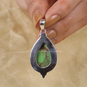 May include: A silver pendant with a green turquoise stone set in a teardrop shape. The pendant has a bail at the top for attaching to a chain.