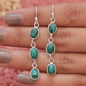 May include: Silver dangle earrings with four oval-shaped green malachite stones.