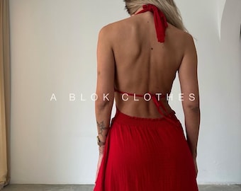 Puede incluir: Vestido rojo con cuello halter y espalda descubierta. El vestido tiene una falda fluida y un lazo en el cuello. El texto "A BLOK CLOTHES" está impreso en la imagen.