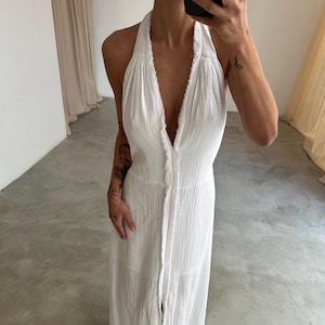May include: A white halter maxi dress with a button-up front and a frayed hem.