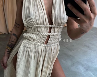 May include: A cream-colored maxi dress with a plunging neckline and high side slits. The dress features a braided waist detail and the text "BLOW CLOTHES". The fabric has a textured, pleated appearance.