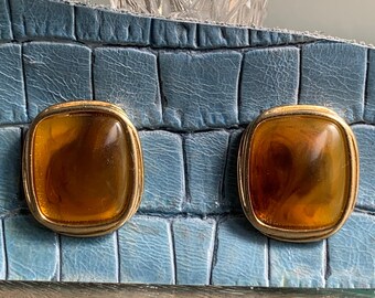 Könnte beinhalten: Ein Paar goldfarbene Ohrclips mit bernsteinfarbenen Glassteinen.