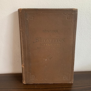 Pode incluir: Um livro castanho com letras douradas na capa. O título é "A Szavatyuk Szerkezete" de Paks Andor.