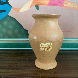 May include: A light brown ceramic vase with a label that reads "Vieux Gres".
