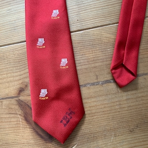 Puede incluir: Corbata de seda roja con un patrón repetido de una computadora y el texto "Class '98". La corbata tiene una etiqueta de texto azul y blanco que dice "The Tie Bar".