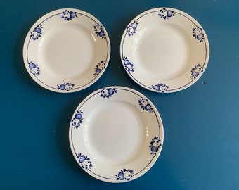 Può includere: Tre piatti in ceramica bianca con un motivo floreale blu e bianco. I piatti hanno un design semplice e classico con un motivo floreale blu attorno al bordo.