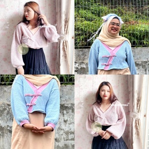 May include: Four different models are wearing a light blue and pink knitted cardigan with a button closure. The cardigan is cropped and has long sleeves. The models are wearing the cardigan with different outfits, including a black skirt, a brown skirt, and a black dress.