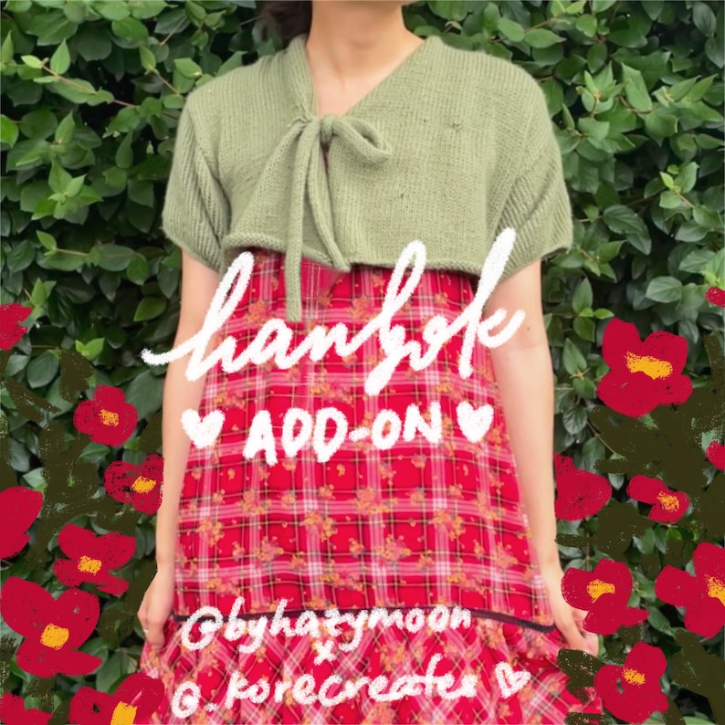 Op de afbeelding: Een groene gebreide cropped cardigan met een strik aan de voorkant, gedragen over een rood-wit geruite jurk met bloemenaccenten. De tekst "handmade ADD-ON" is in wit op de jurk geschreven. De tekst "@byhatymoon x @korecreates" is in zwart onderaan de jurk geschreven.
