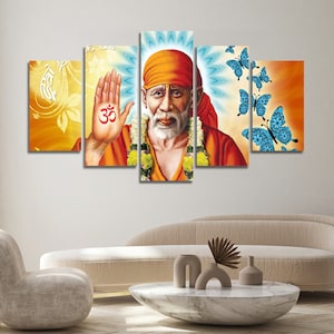 Puede incluir: Un conjunto de cinco impresiones en lienzo que presenta un retrato de Sai Baba, un líder espiritual hindú, con un símbolo Om rojo en su mano. El fondo presenta un diseño de mandala azul y blanco y mariposas azules.