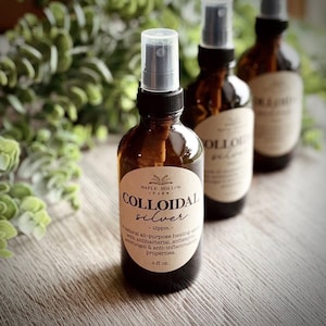 Op de afbeelding: Drie bruine glazen spuitflessen met witte etiketten zijn in een rij gerangschikt. De etiketten lezen "Colloïdaal Zilver" en bevatten tekst over de eigenschappen ervan. Elke fles bevat 118 ml.