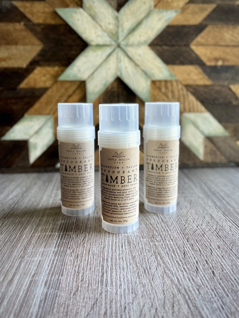May include: Three white deodorant tubes with brown labels. The labels read "Magnesium Tallow Deodorant" and "TAMBER" with a description of the scent "cedarwood + palo santo".