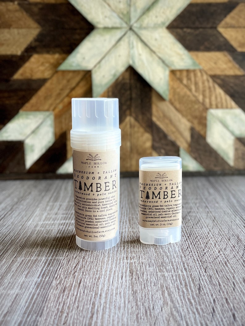 May include: Two deodorant sticks in clear plastic containers with brown labels. The labels read "Magnesium + Tallow Deodorant Tamber Cedarwood + Palo Santo" and include the brand name "Maple Hollow Farm". The larger stick is 2 oz and the smaller stick is .5 oz.