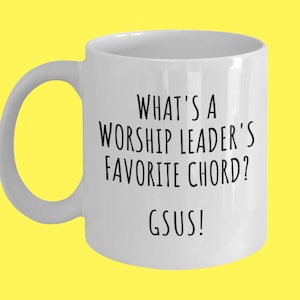 May include: White ceramic coffee mug with black text that reads "What's a worship leader's favorite chord? Gsus!"
