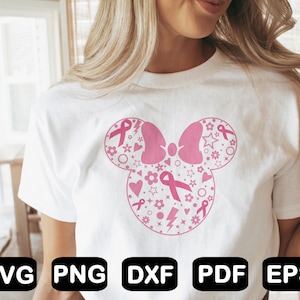May include: A white t-shirt with a pink and white design of a Mickey Mouse head with pink ribbons and stars. The design is a symbol of breast cancer awareness.