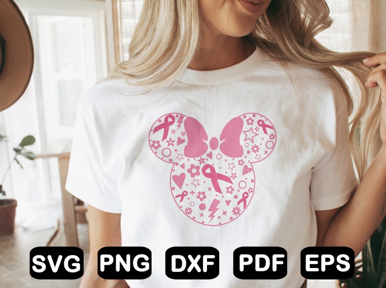 May include: A white t-shirt with a pink and white design of a Mickey Mouse head with pink ribbons and stars. The design is a symbol of breast cancer awareness.
