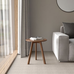 May include: A round wooden side table with three legs. The table is made of dark wood and has a natural finish. There are two books and a pair of glasses on top of the table.