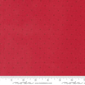 May include: Red fabric with a repeating pattern of small, evenly spaced brown dots. The fabric has a textured appearance and a ruler is visible along the bottom edge. The fabric is likely used for quilting or other craft projects.