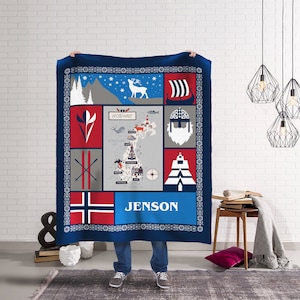 May include: A blue and red fleece blanket with a map of Norway, a Viking ship, a reindeer, skis, a lighthouse, a compass, and a Norwegian flag. The blanket has the name "Jenson" printed on it.