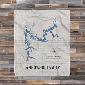 May include: A white throw blanket with a blue map of Lake Allatoona, Georgia. The coordinates of the lake are printed below the map. The text "Jankowski Family" is printed below the coordinates.