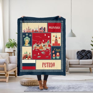 May include: A blue and red fleece blanket with a patchwork design featuring iconic Russian imagery, including the Kremlin, a map of Russia, and nesting dolls. The text "RUSSIA" and "PSTROV" are printed on the blanket.