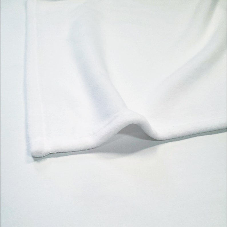 May include: White fabric with a soft, fuzzy texture. The fabric is folded over on itself, showing the edge of the material.