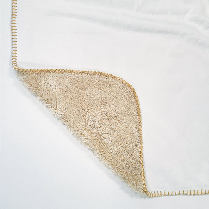 May include: A white blanket with a tan fleece lining. The blanket has a gold stitched border.
