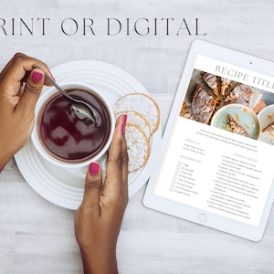 May include: A white tablet displaying a recipe titled "RECIPE TITLE" with a photo of a dessert. The recipe includes ingredients and instructions. The tablet is on a white wooden surface with a cup of tea and cookies.