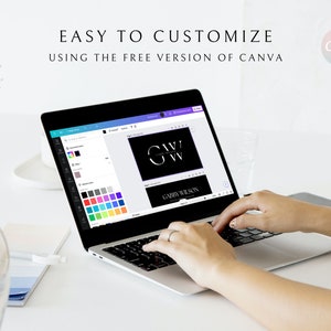 May include: A laptop screen shows a Canva design with a black background and white text that reads "G.A.W.V. GABBY WILSON". The screen shows a color palette with various shades of blue, green, purple, and gray. The laptop is on a white desk with a person's hands typing on the keyboard.