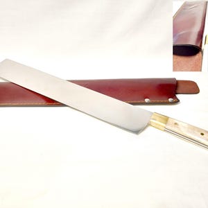 Peut inclure: Un long couteau de cuisine à lame droite en argent poli, doté d'une mitre en laiton et d'un manche de couleur claire fixé par trois rivets. Le couteau est accompagné d'un étui en cuir brun rougeâtre foncé avec des coutures visibles.