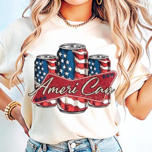 May include: Cream-colored t-shirt featuring a graphic of three beverage cans with a red, white, and blue American flag design. The cans are arranged in a row, with the text "Ameri Can" in a red banner.