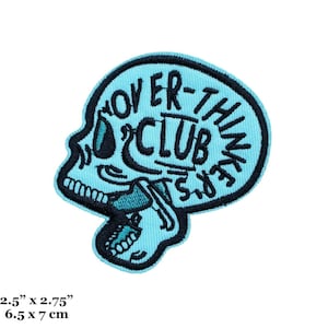 May include: A light blue embroidered patch with a skull outline and the text "Over-Thinkers Club" inside. The patch is 2.5 inches by 2.75 inches.