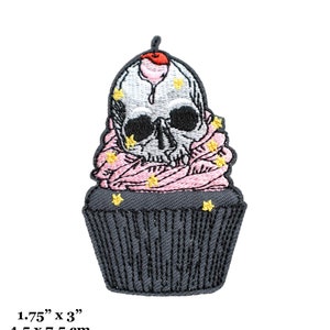 Può includere: Un toppa da stirare ricamata in nero e rosa a forma di cupcake con un teschio per la glassa e una ciliegia rossa in cima. Il cupcake è decorato con stelle gialle. La toppa misura 4,5 cm per 7,5 cm.