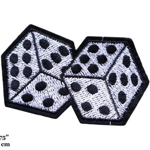 May include: Two embroidered dice patches. Each patch is a white hexagon with black dots, outlined in black. The patches measure 8 cm by 4.5 cm.